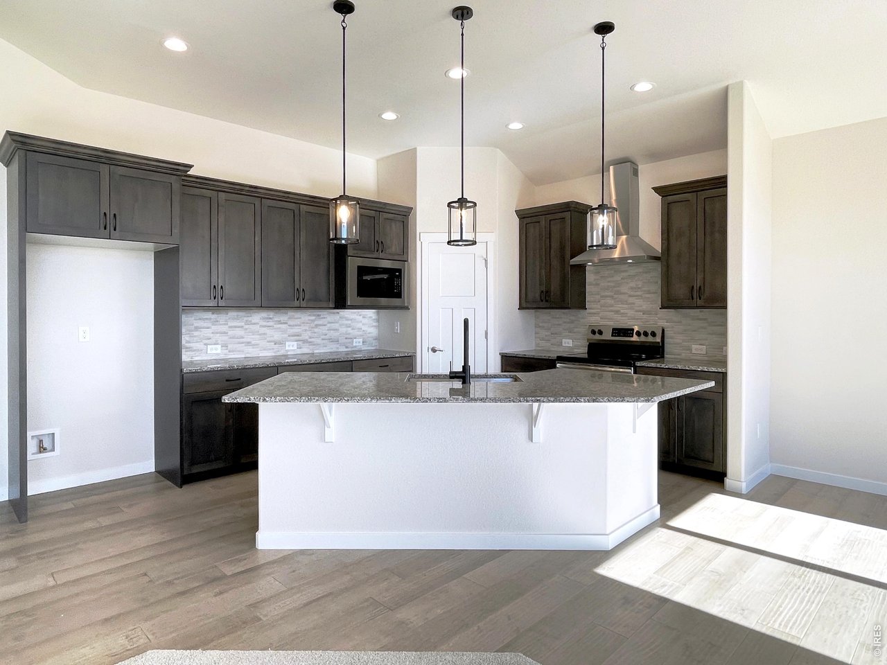1145 Bitterroot Court Johnstown, CO 80534 - Photo 6 of 31 a large kitchen with stainless steel appliances kitchen island granite countertop a refrigerator a oven and a wooden floor