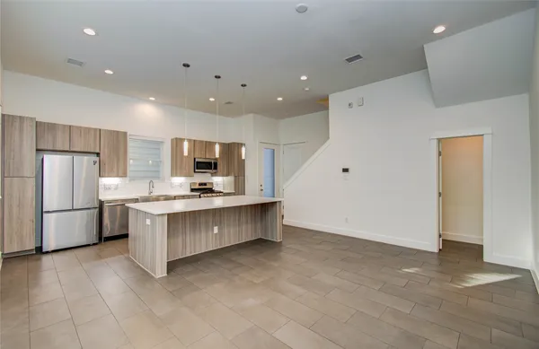 a large kitchen with kitchen island a large counter top stainless steel appliances and cabinets