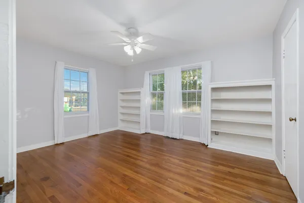 a view of an empty room with a window and wooden floor