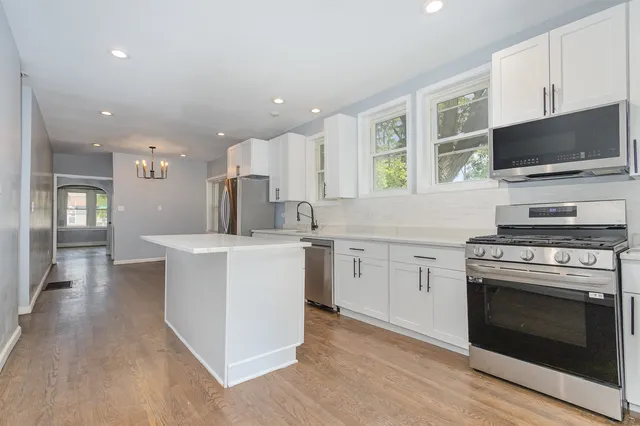 a kitchen with kitchen island granite countertop a sink cabinets and stainless steel appliances