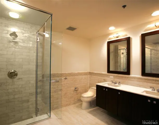 a bathroom with a double vanity sink toilet and shower