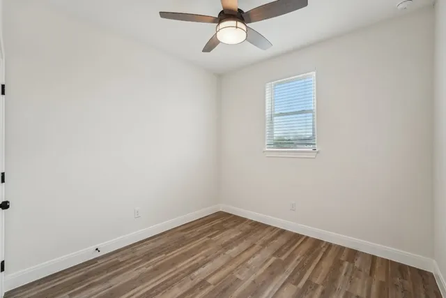 an empty room with a window and ceiling fan