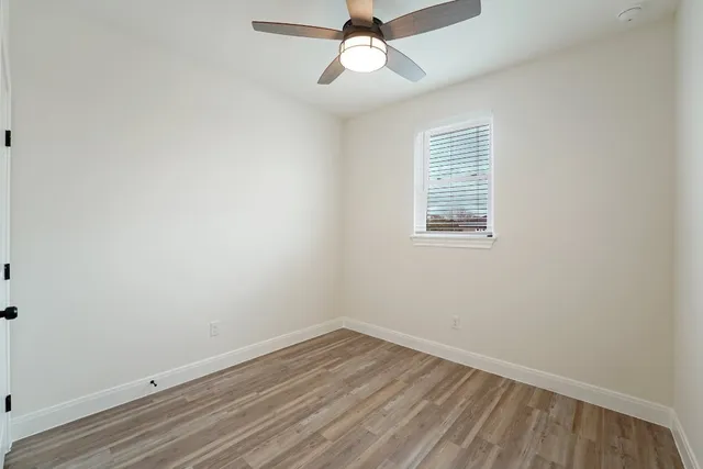 an empty room with a window and ceiling fan