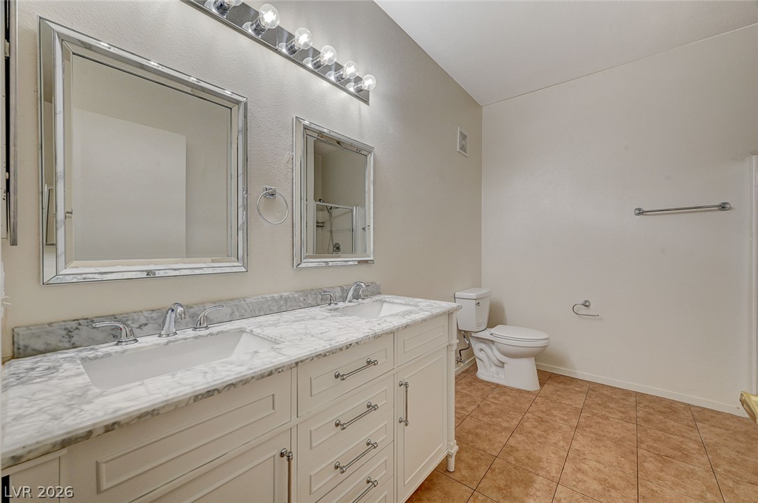 9050 West Warm Springs Road, Unit 1147 Las Vegas, NV 89148 - Photo 27 of 36 Marble-topped double vanity with undermount sinks, set on warm tiled flooring.