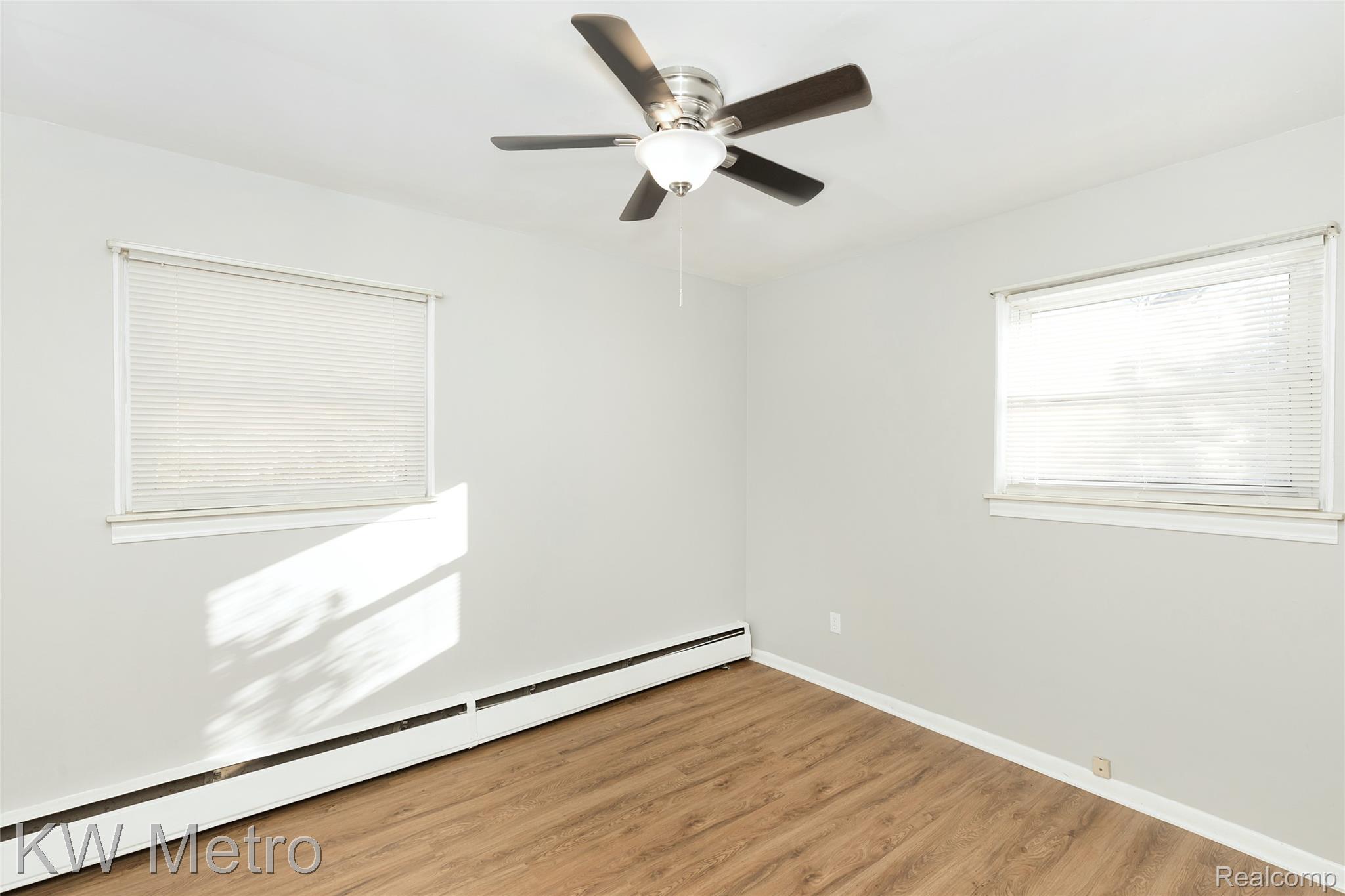 2817 West 13 Mile Road Royal Oak, MI 48073 - Photo 14 of 21 Unfurnished room featuring a baseboard heating unit, light wood-style floors, and ceiling fan