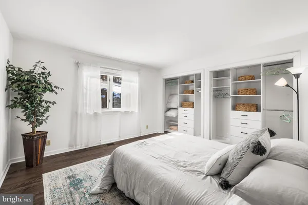 a large kitchen with a refrigerator a sink dishwasher stove and white cabinets with wooden floor