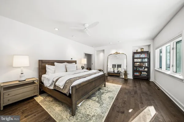 a spacious bedroom with a bed a dresser and a large window