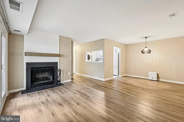 a view of empty room with wooden floor and fireplace