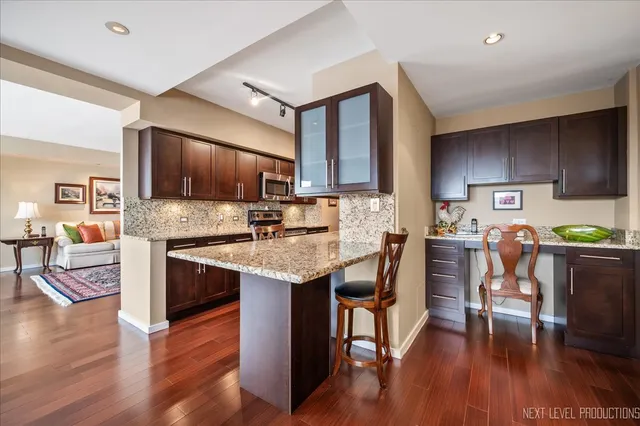 a kitchen with stainless steel appliances granite countertop a stove top oven a sink dishwasher a dining table and chairs with wooden floor