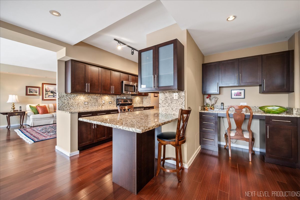 3180 North Lake Shore Drive, Unit 5E Chicago, IL 60657 - Photo 10 of 28 a kitchen with stainless steel appliances kitchen island granite countertop a stove a sink a microwave and a refrigerator