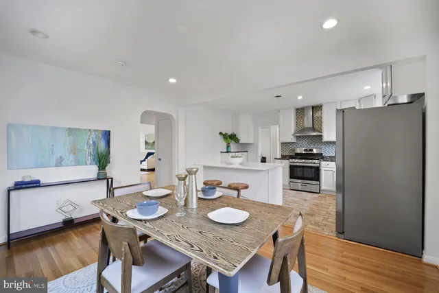 a kitchen with stainless steel appliances granite countertop a dining table chairs refrigerator and microwave