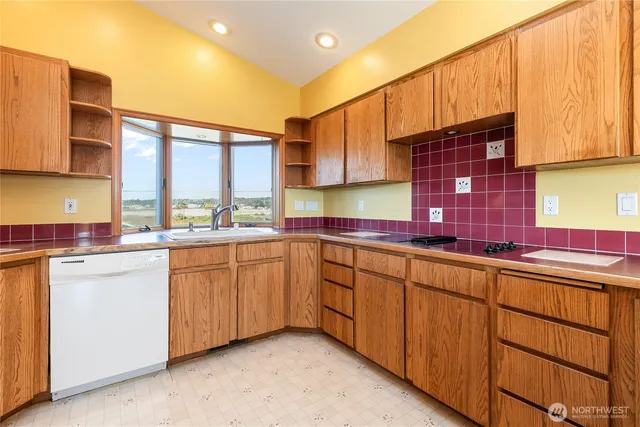 a kitchen with granite countertop a sink stainless steel appliances wooden cabinets and a window