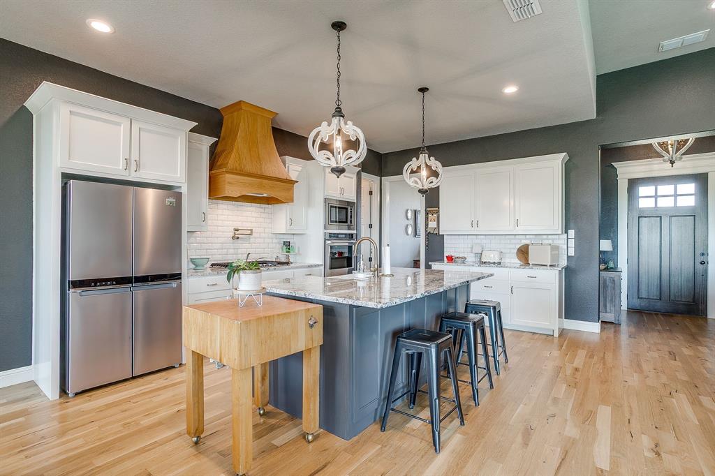 116 Aviara Ridge Road Poolville, TX 76487 - Photo 14 of 38 a kitchen with stainless steel appliances granite countertop a refrigerator a sink dishwasher a stove and a dining table with wooden floor