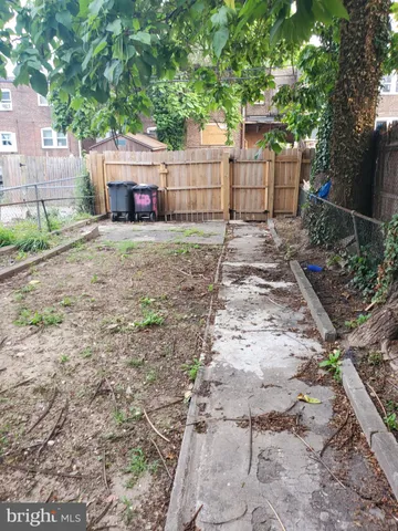 a view of a backyard with large trees and wooden fence