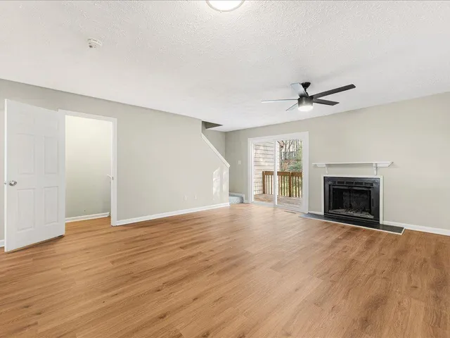 a view of an empty room with wooden floor fireplace and a window
