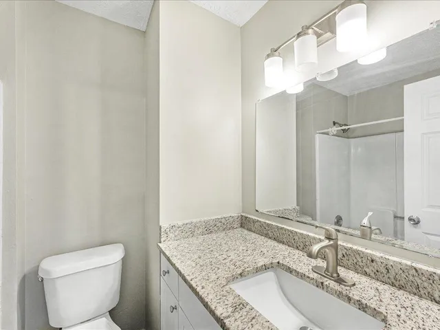 a bathroom with a granite countertop sink a toilet and a mirror