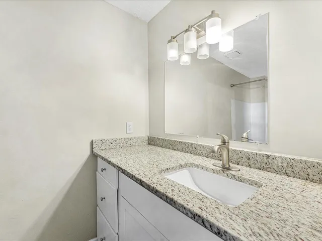 a bathroom with a granite countertop sink a mirror and a vanity