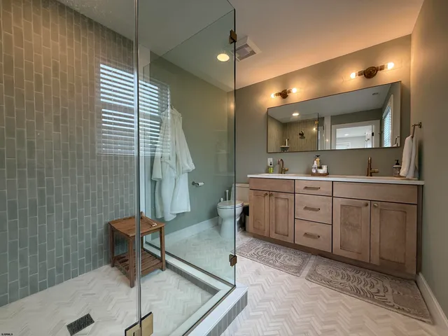 a bathroom with a sink a toilet a mirror and shower