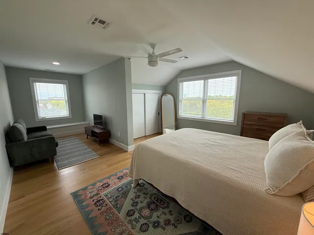 a spacious bedroom with a bed and wooden floor