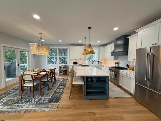 a kitchen with stainless steel appliances granite countertop a table chairs sink and cabinets