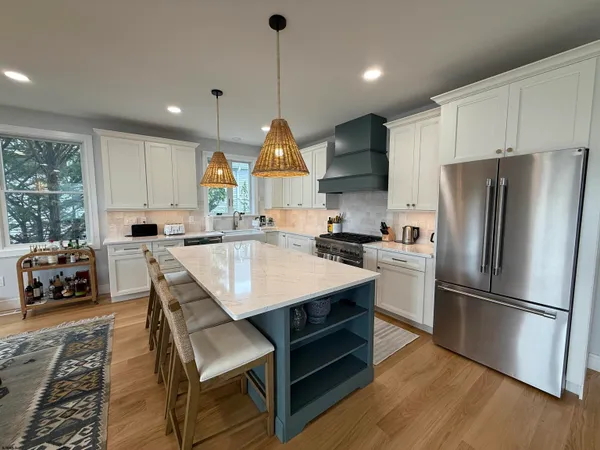 a kitchen with stainless steel appliances granite countertop a sink a stove a refrigerator and island with wooden floor