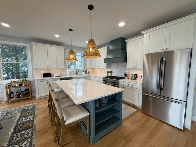 a kitchen with stainless steel appliances granite countertop a sink a stove a refrigerator and island with wooden floor