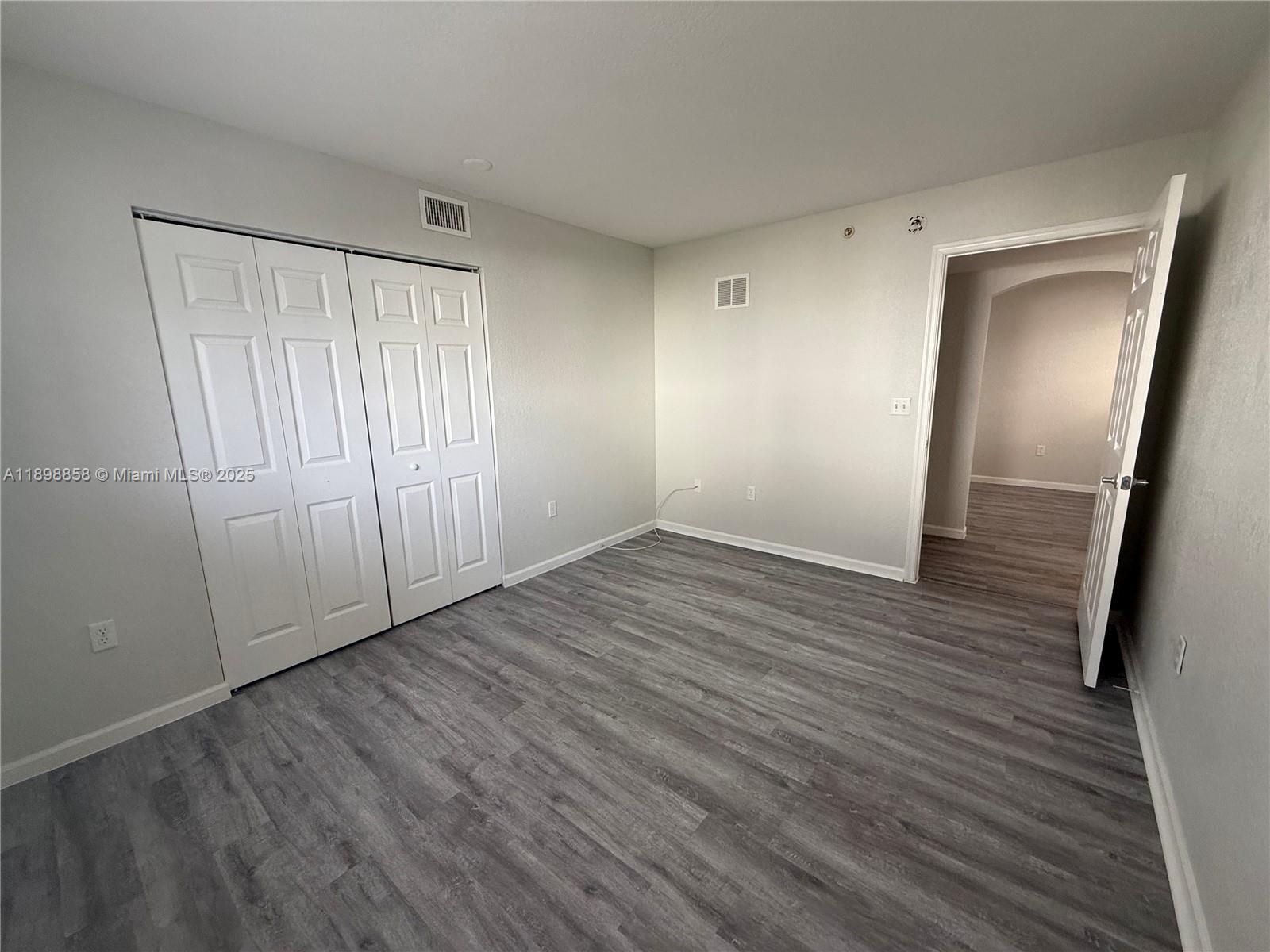 3452 Cypress Trail, Unit 101 West Palm Beach, FL 33417 - Photo 13 of 29 a view of an empty room with wooden floor and a window