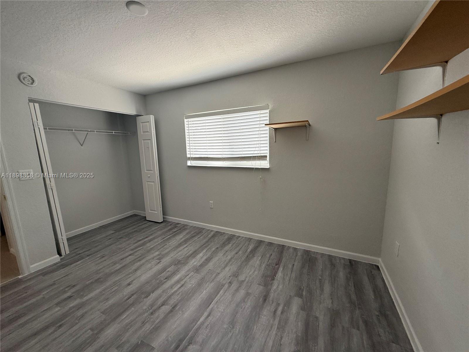 3452 Cypress Trail, Unit 101 West Palm Beach, FL 33417 - Photo 6 of 29 an empty room with wooden floor and windows