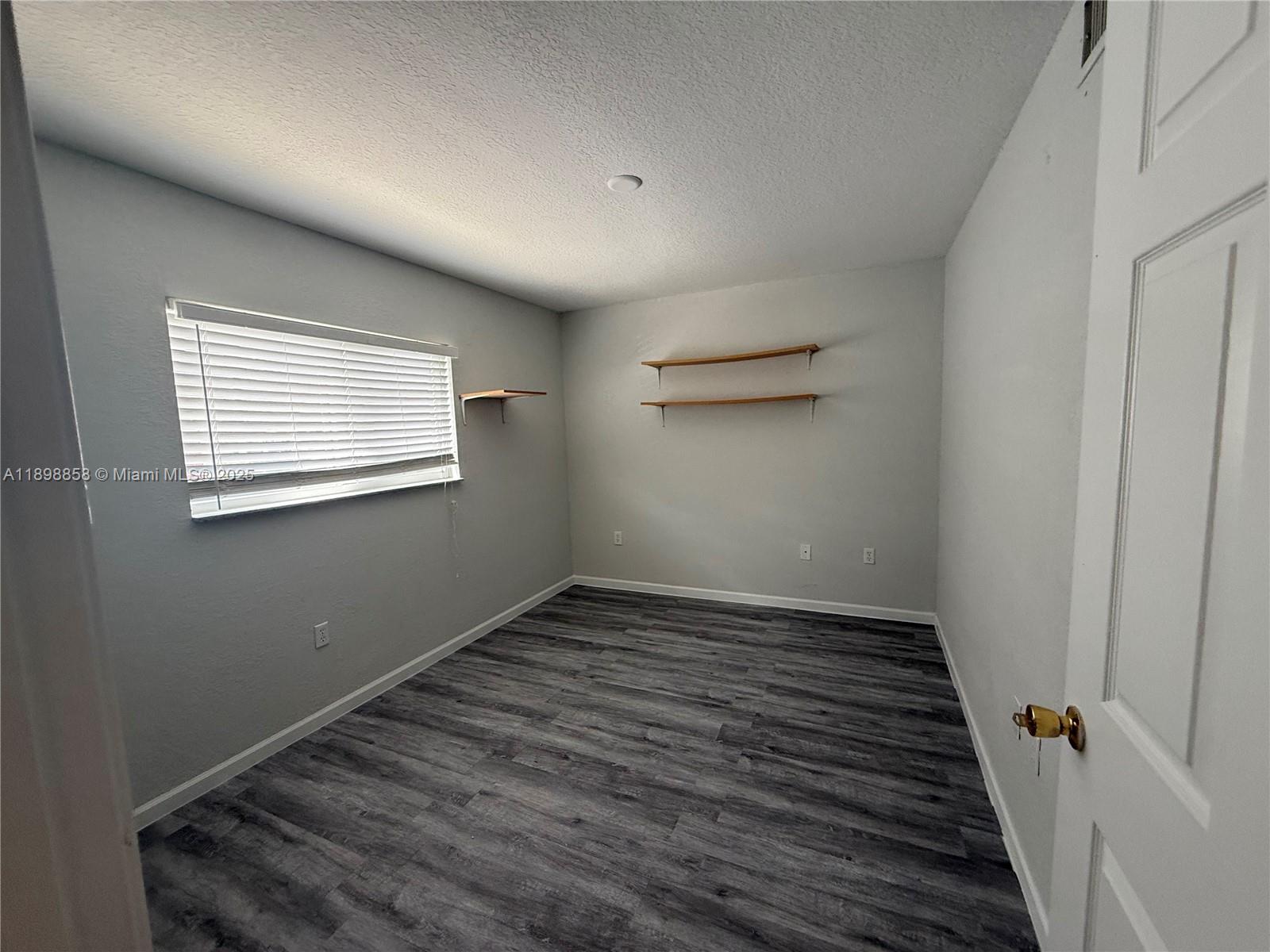 3452 Cypress Trail, Unit 101 West Palm Beach, FL 33417 - Photo 7 of 29 a view of an empty room with wooden floor and a window