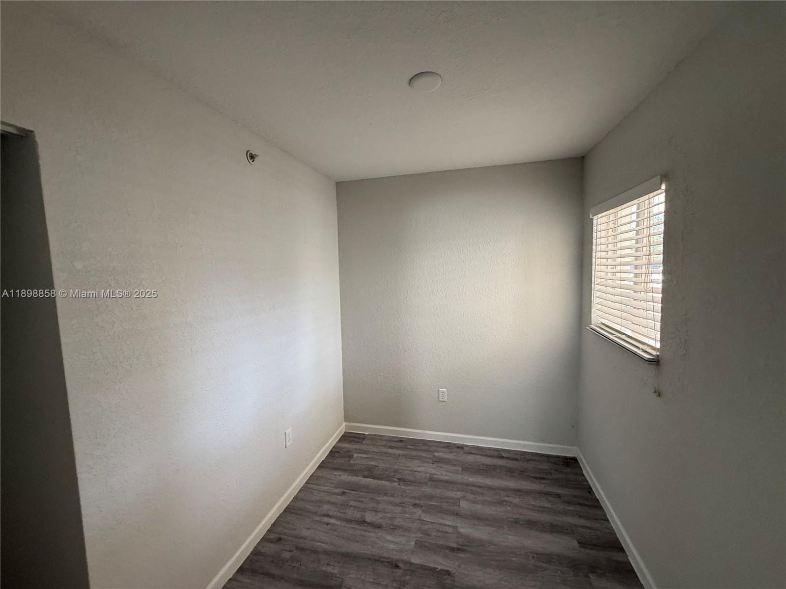 3452 Cypress Trail, Unit 101 West Palm Beach, FL 33417 - Photo 10 of 29 a view of an empty room with wooden floor and a window
