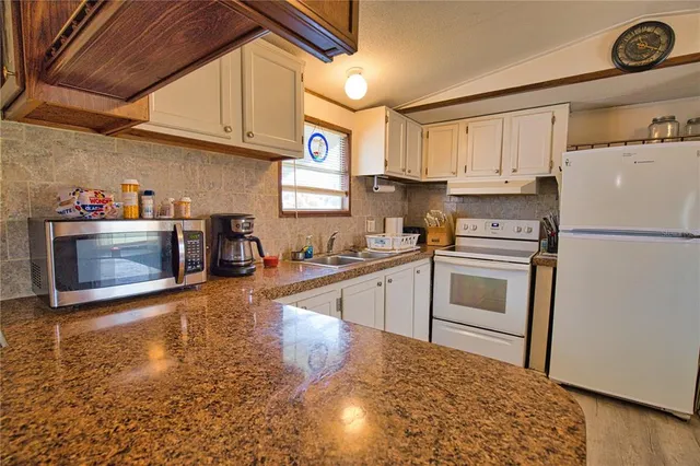 a kitchen with granite countertop a refrigerator stove and sink