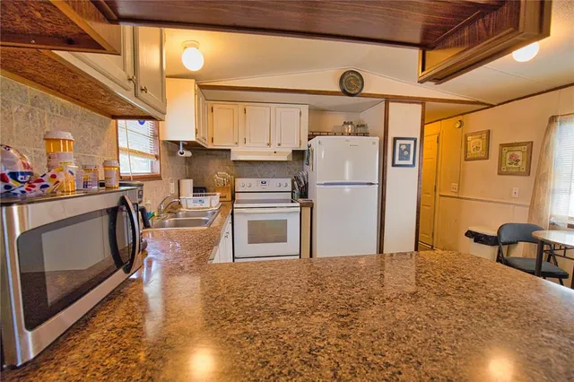 a kitchen with stainless steel appliances granite countertop a refrigerator a stove a sink dishwasher and white cabinets with wooden floor