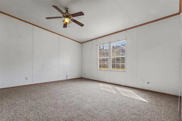 an empty room with ceiling fan and window