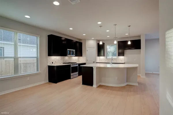 a large kitchen with stainless steel appliances kitchen island granite countertop a stove top oven and a sink with granite countertops
