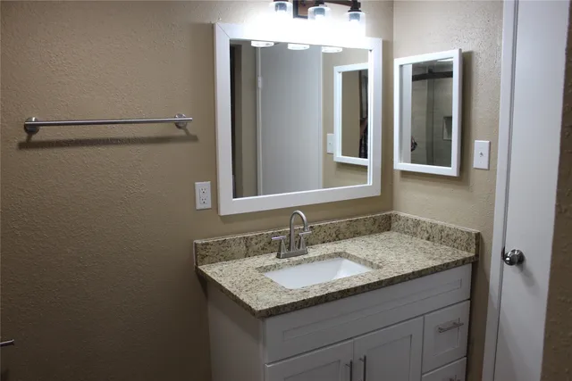 a bathroom with a granite countertop sink and a mirror