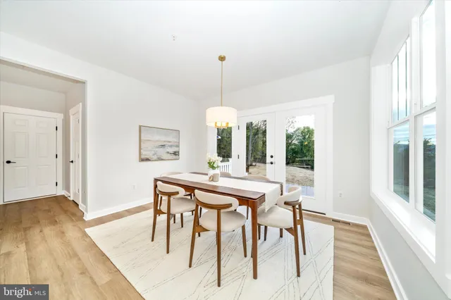 a dining room with wooden floor a chandelier a wooden table and chairs