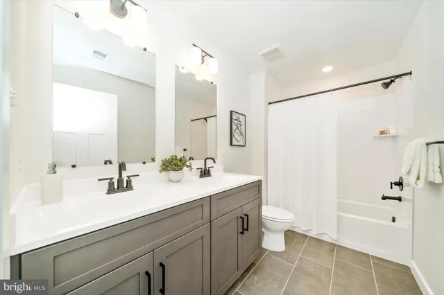 a bathroom with a double vanity sink toilet mirror and shower