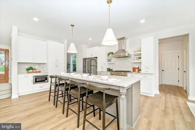 a kitchen with stainless steel appliances granite countertop a stove a sink dishwasher a stove a dining table with chairs and wooden floor