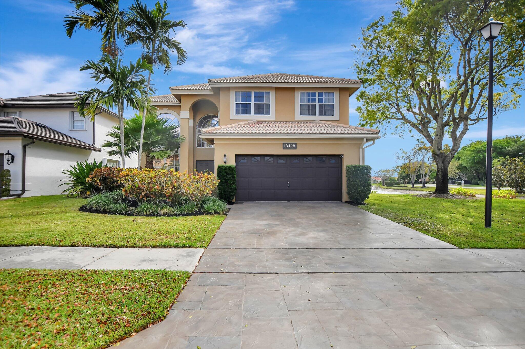 18498 East Covington Trace Boca Raton, FL 33498 - Photo 3 of 62 a front view of a house with a garden and trees
