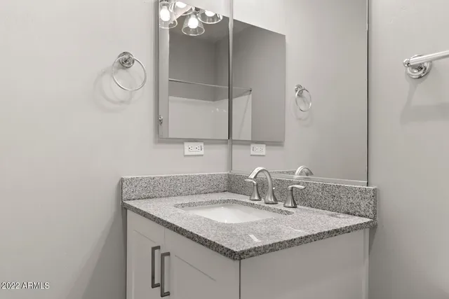 a bathroom with a granite countertop sink and a mirror