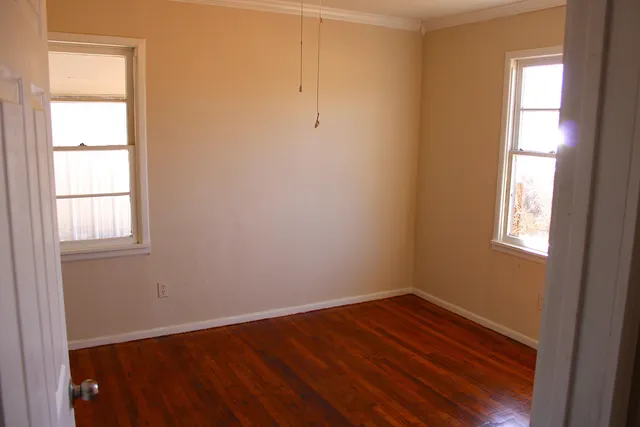 an empty room with wooden floor and windows