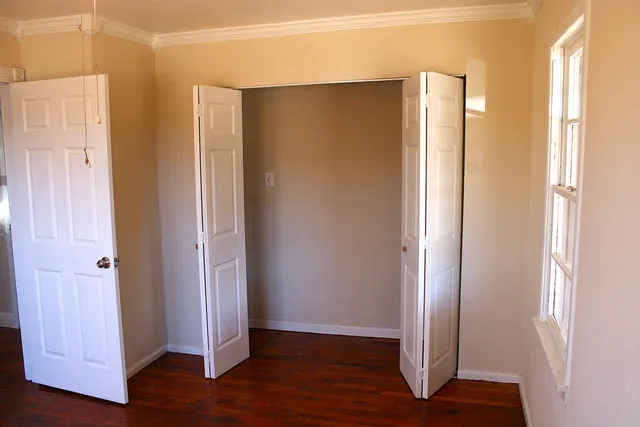 an empty room with wooden floor and windows