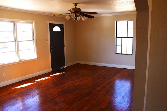 a view of an empty room with wooden floor and a window