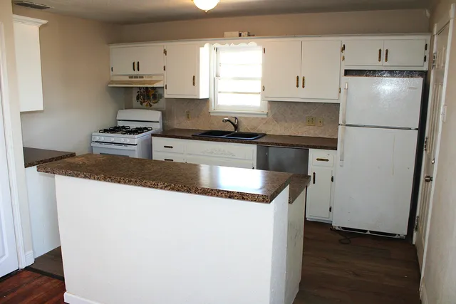 a kitchen with granite countertop a refrigerator sink and stove
