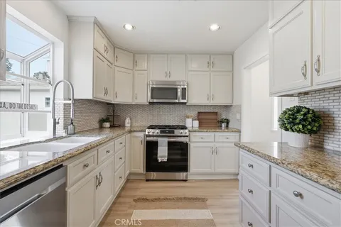 a kitchen with granite countertop white cabinets and stainless steel appliances