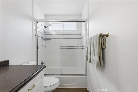a bathroom with a granite countertop bathtub shower sink vanity and toilet