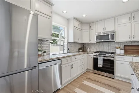 a kitchen with stainless steel appliances granite countertop a stove a sink and a microwave