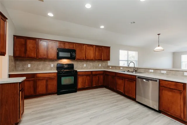 a large kitchen with granite countertop wooden cabinets a stove a sink and dishwasher
