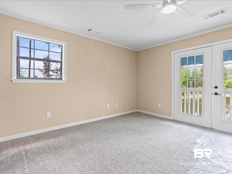 3160 Old Castleberry Road Brewton, AL 36426 - Photo 13 of 36 Light-filled room featuring neutral-toned walls, gray carpeting, and a ceiling fan with integrated lighting