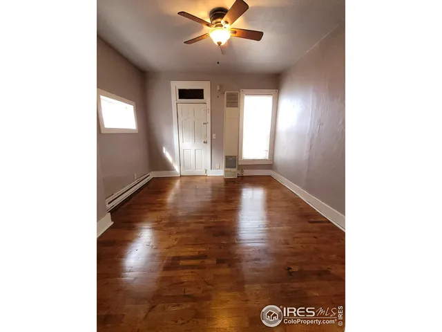 a view of an empty room with window and wooden floor
